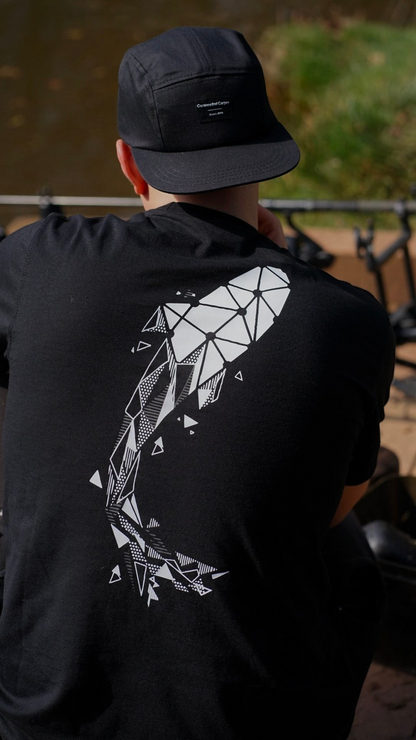 Connected Carper black t-shirt with a large white geometric carp fish graphic on the back, worn by a fisherman.
