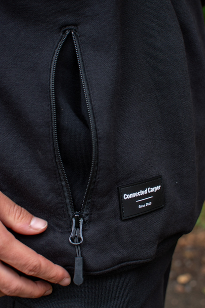 Connected Carper black hoodie featuring a discreet zippered pocket and a PVC brand patch on the side.