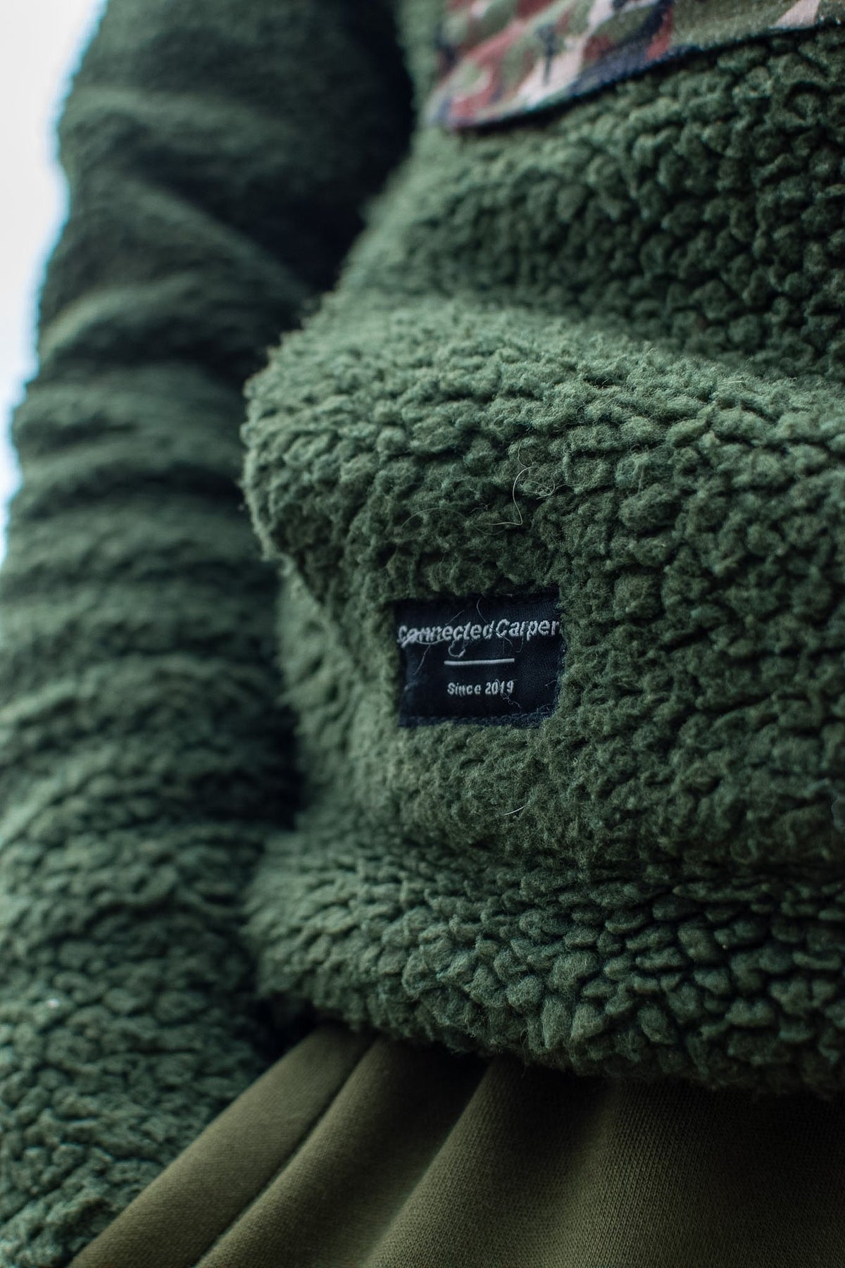 Connected Carper khaki sherpa fleece hoodie with textured fabric and branded patch on the kangaroo pocket