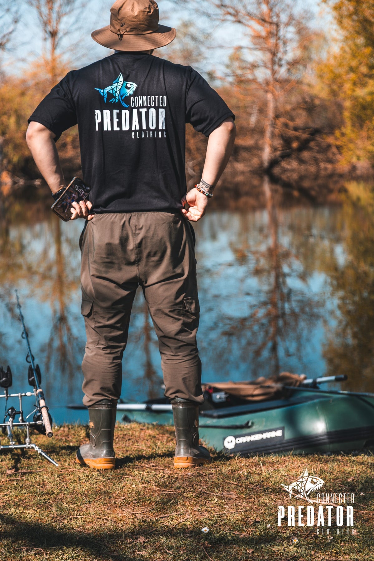 Connected Carper black cotton-blend t-shirt with blue and white Predator logo on back, worn by angler at lakeside
