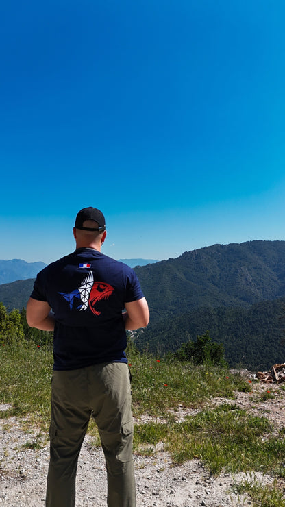 Connected Carper Predator Frenchie t-shirt with a tricolour fish logo worn by a man overlooking a mountain landscape.